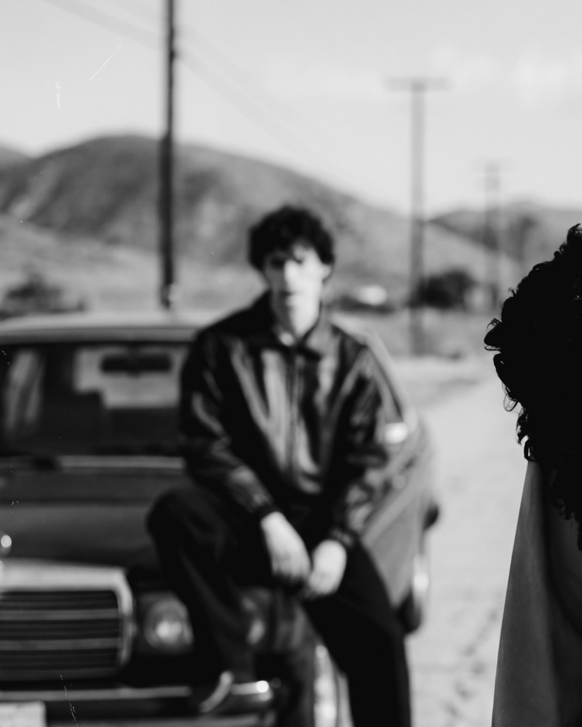 AI product photography — black-and-white e-commerce editorial of a model on a vintage car